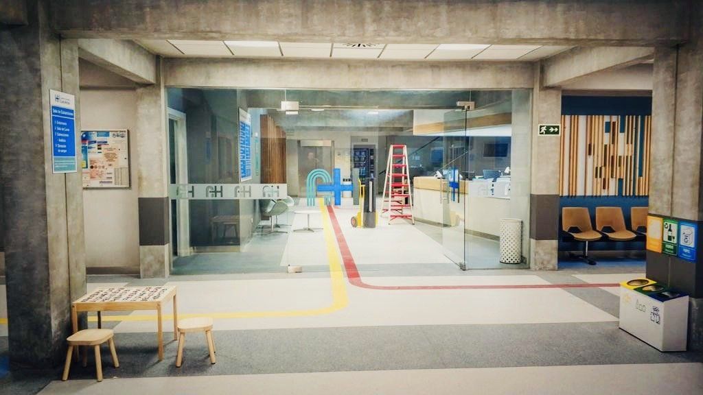 Un pasillo de hospital con una mesa y sillas en el medio.