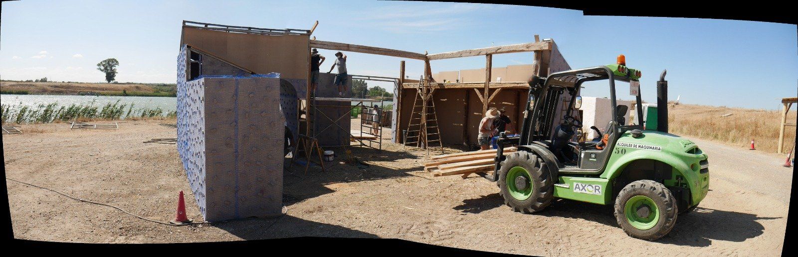 Un tractor verde está estacionado frente a un edificio en construcción.