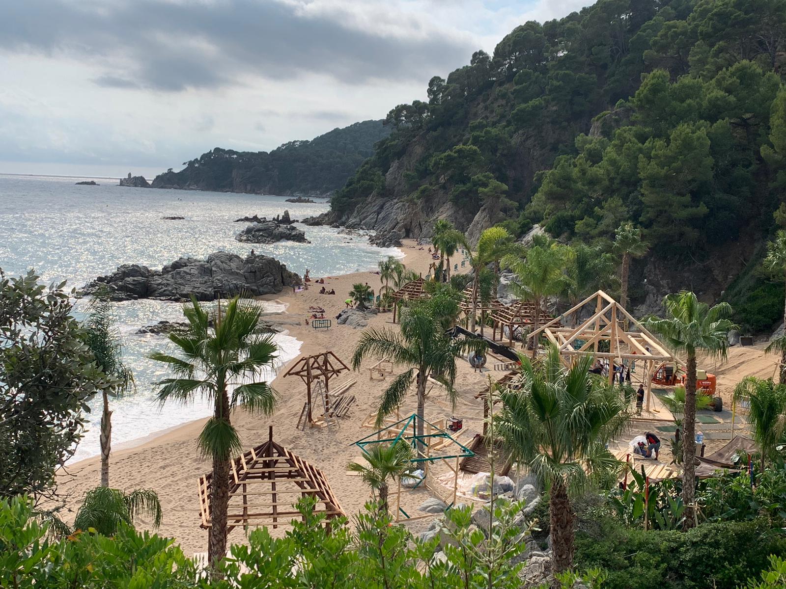 Una playa con palmeras y sombrillas en un día nublado.