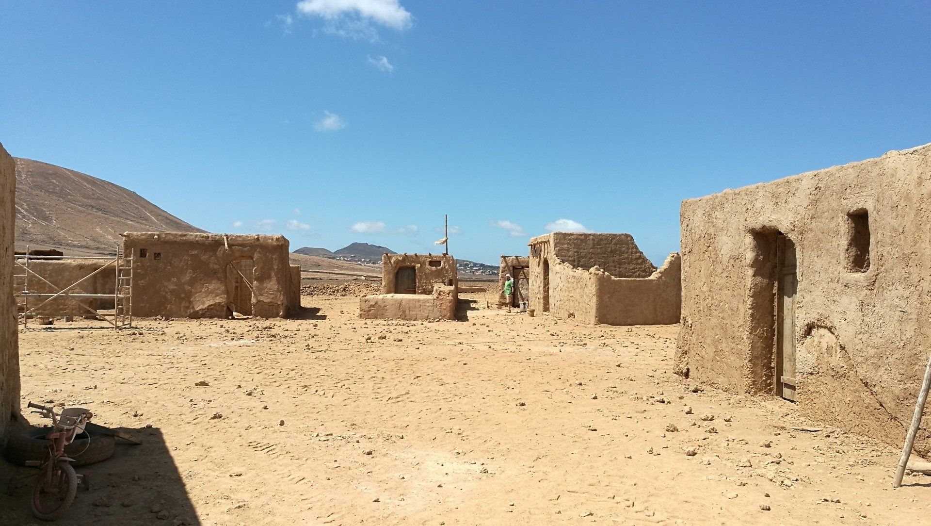 Un paisaje desértico con algunos edificios y montañas al fondo.