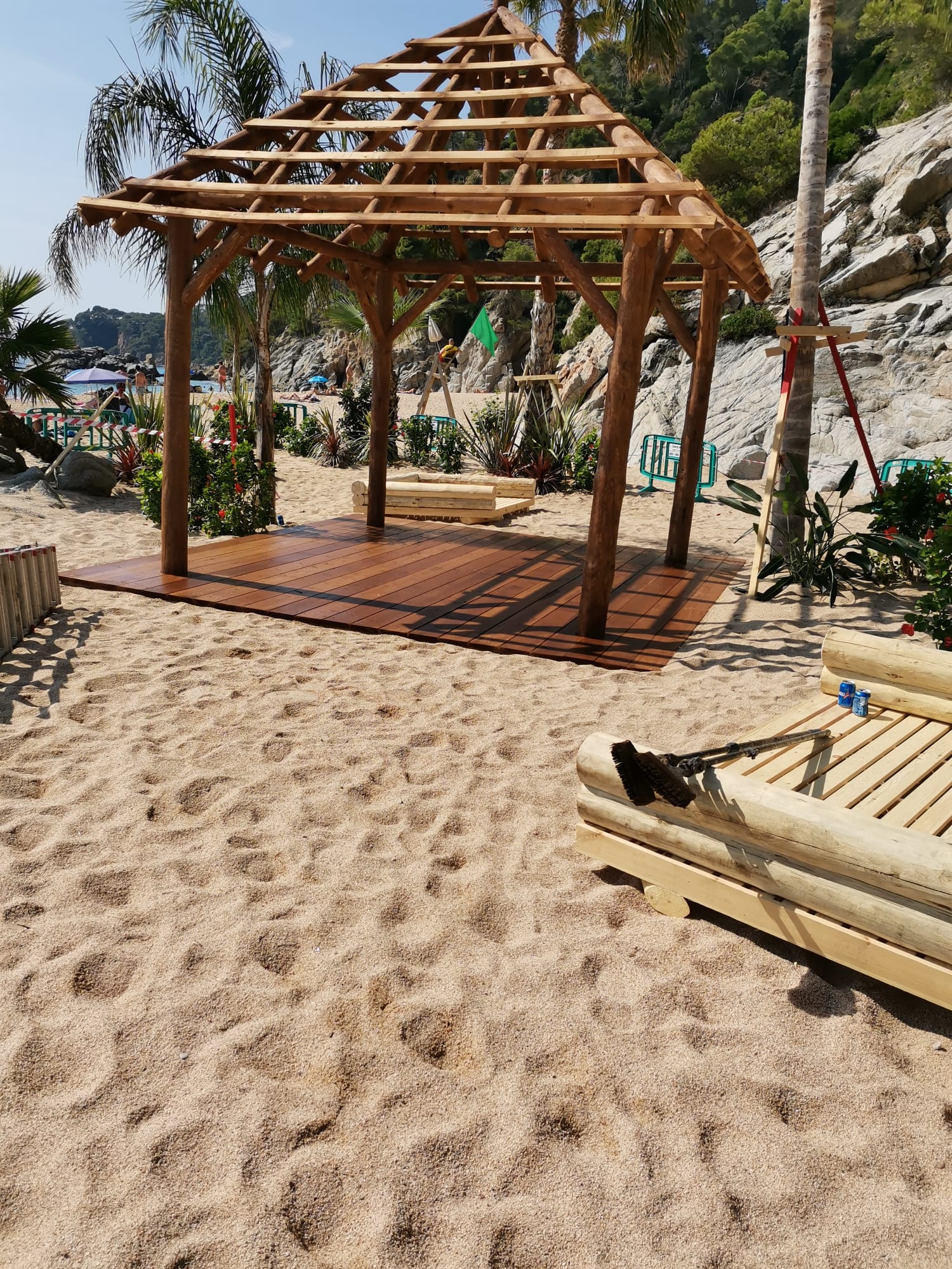 Un cenador de madera está situado encima de una playa de arena.