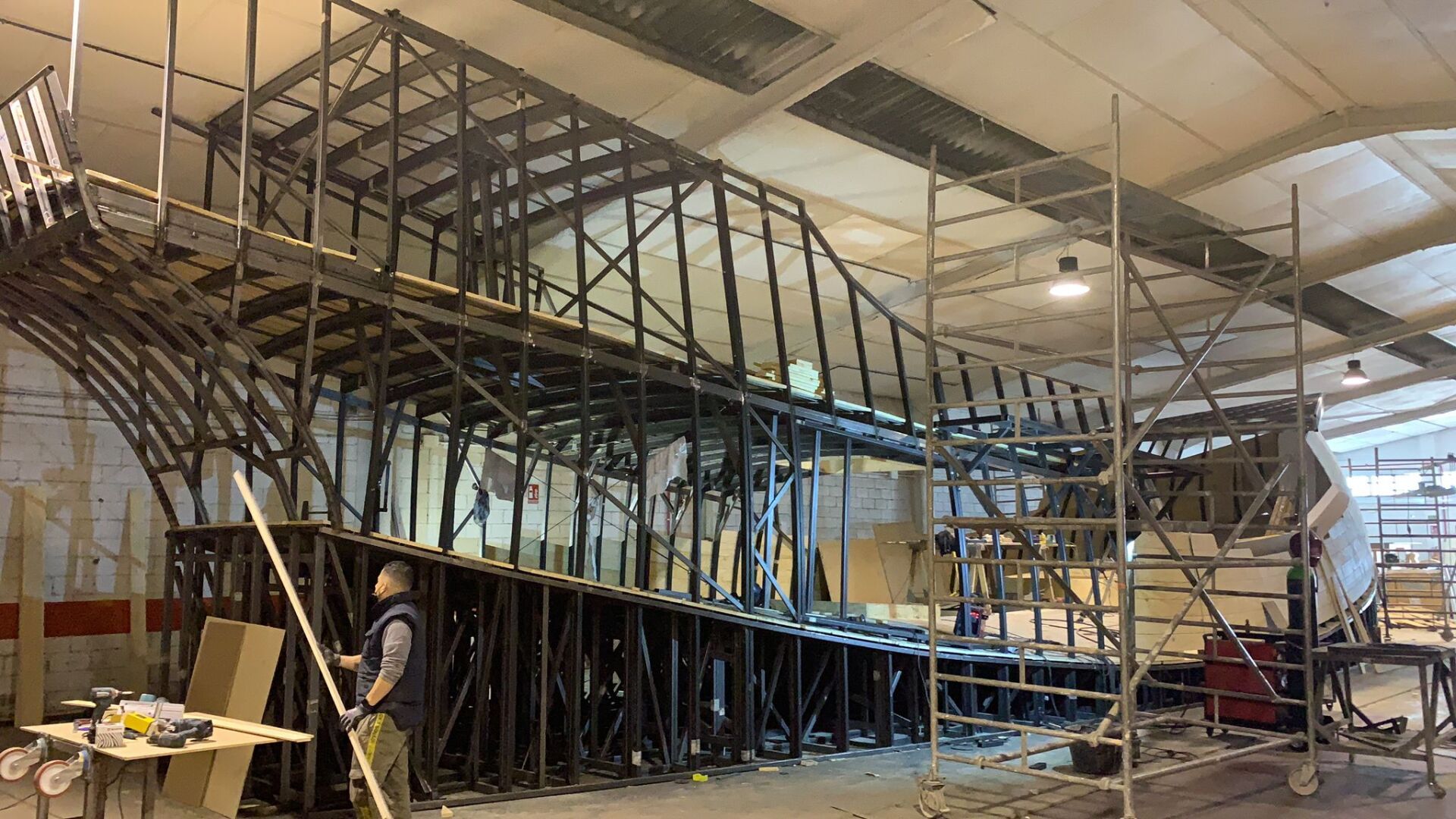 Un hombre está parado frente a una gran estructura de metal en un edificio.