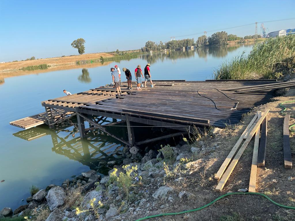 Un grupo de personas está de pie en un muelle de madera al lado de un lago.