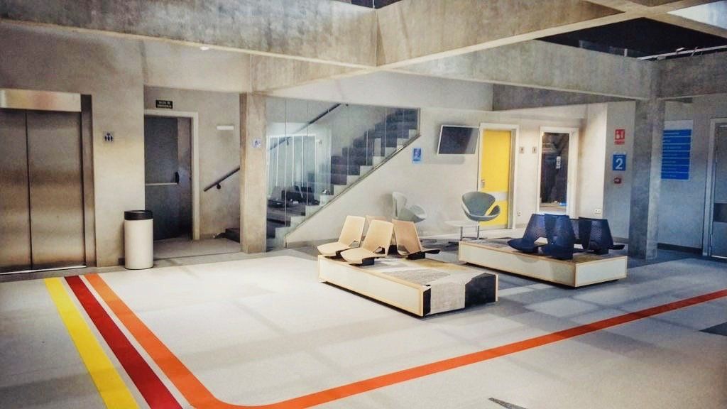 Una sala de espera con muchas sillas y una escalera al fondo.