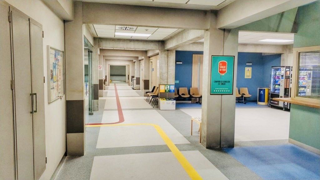 Un largo pasillo en un hospital con una línea amarilla en el suelo.