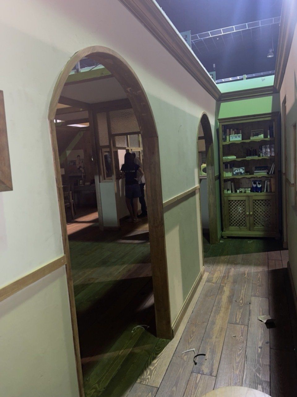 Un pasillo con arcos y un estante en la esquina.