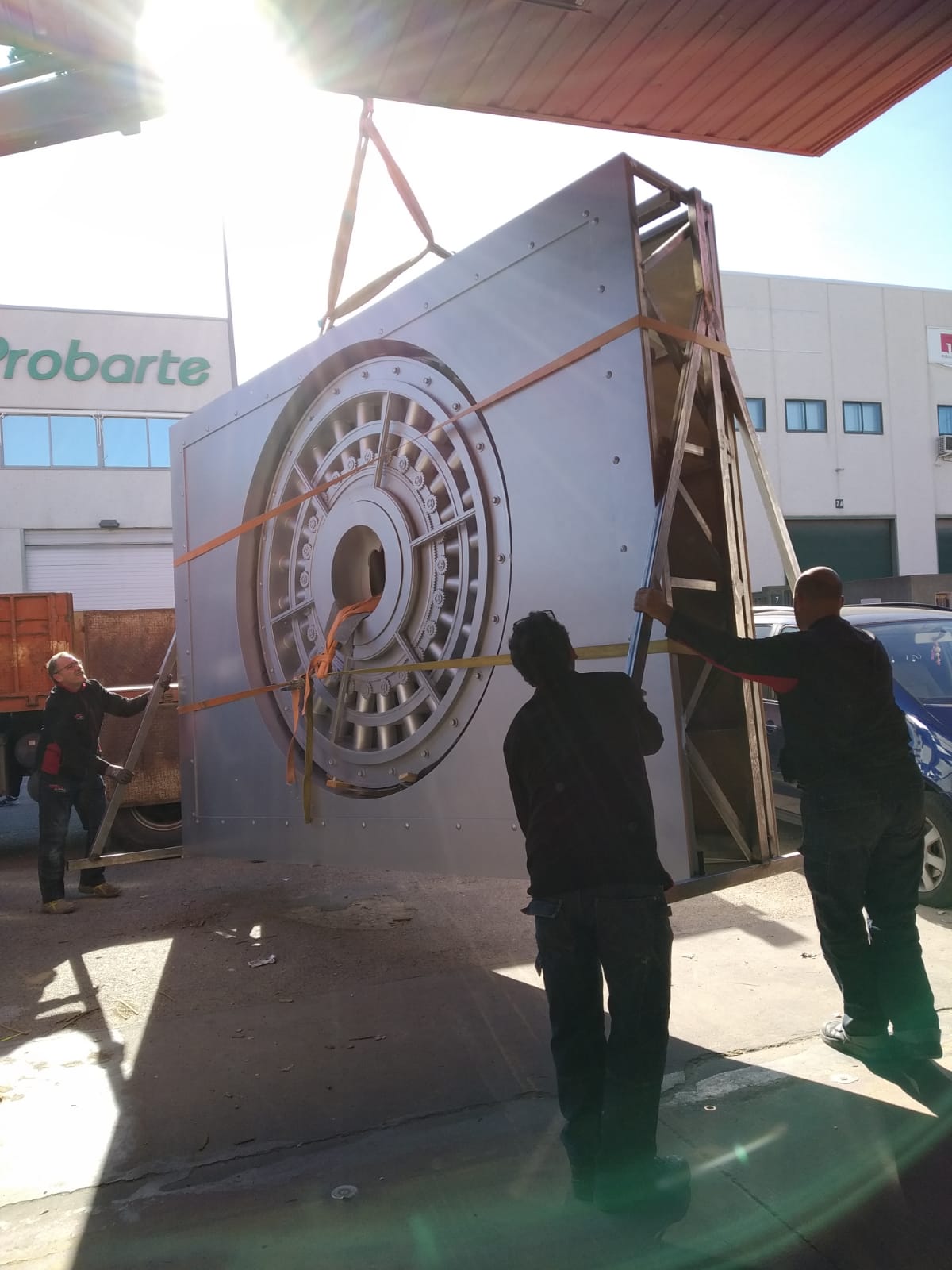 Dos hombres miden un gran objeto metálico frente a un edificio que dice probarte.