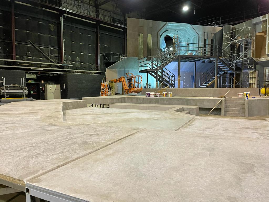 Una habitación grande con suelo de hormigón y escaleras al fondo.