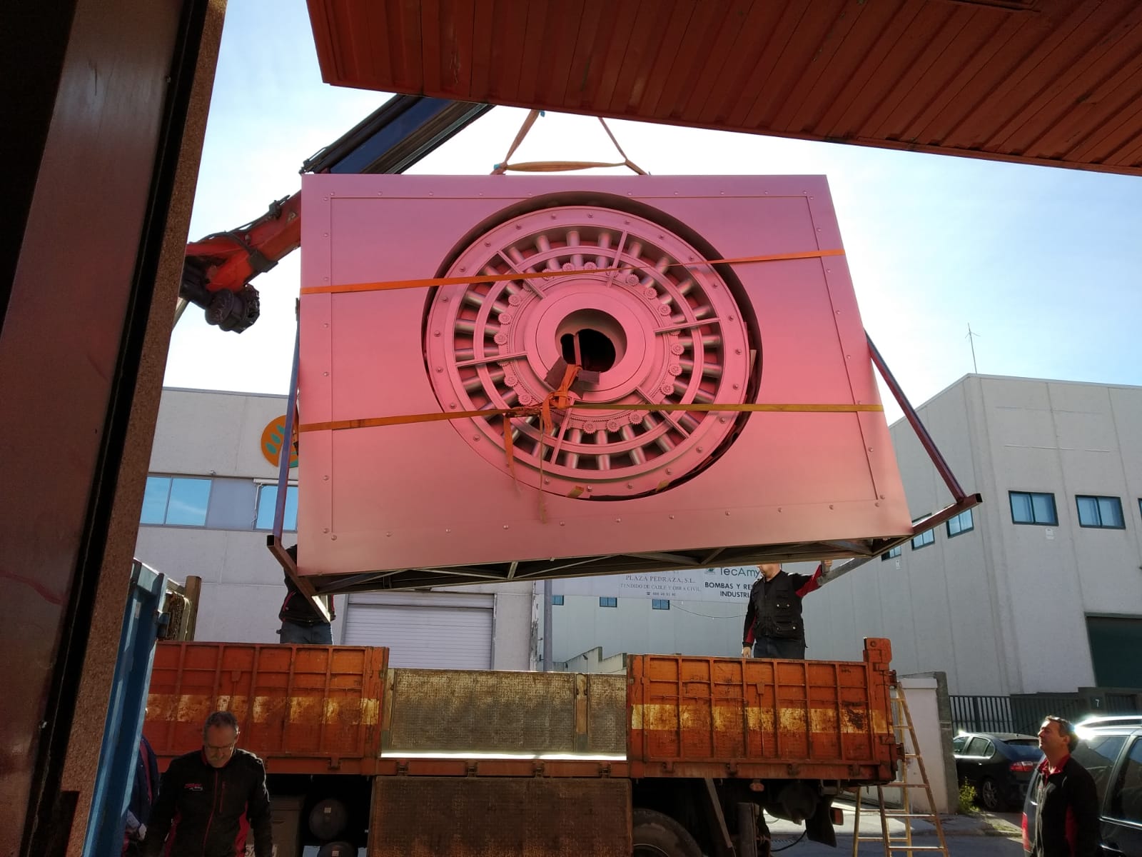 Una grúa levanta una gran pieza de metal.
