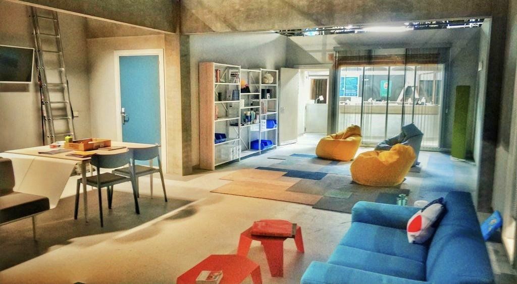 Una sala de estar con un sofá azul y sillones puf amarillos.