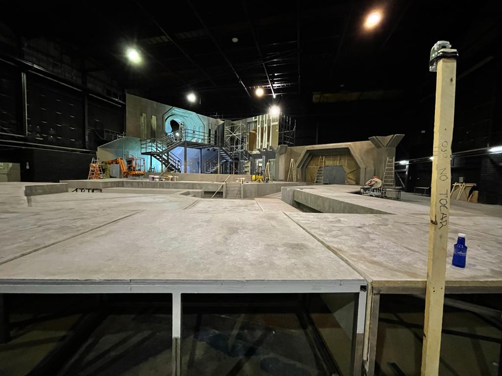 Un escenario vacío en una habitación oscura con un poste de madera en primer plano.