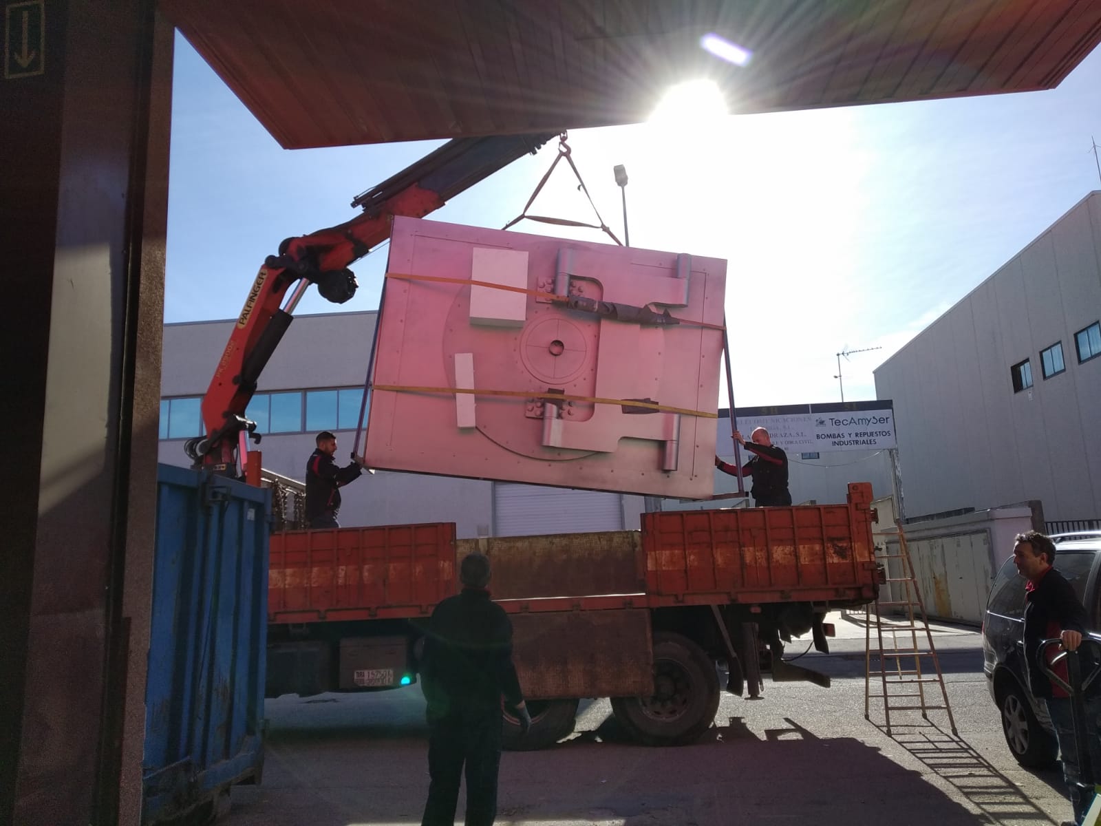 Una grúa está levantando una gran pieza de metal encima de un camión.