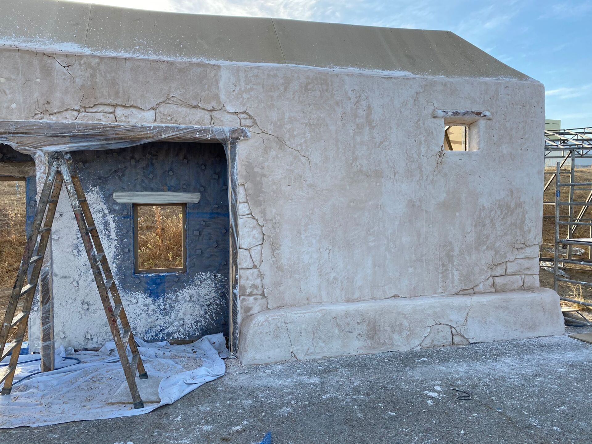 Un edificio blanco con una ventana y una escalera delante.