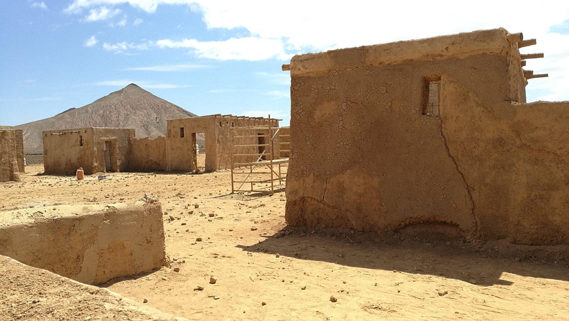 Un paisaje desértico con algunos edificios y una montaña al fondo.