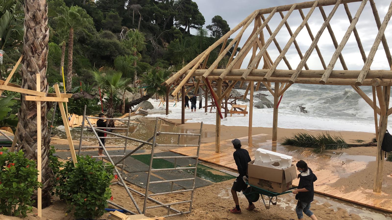 Un grupo de personas está trabajando en una estructura de madera en una playa.