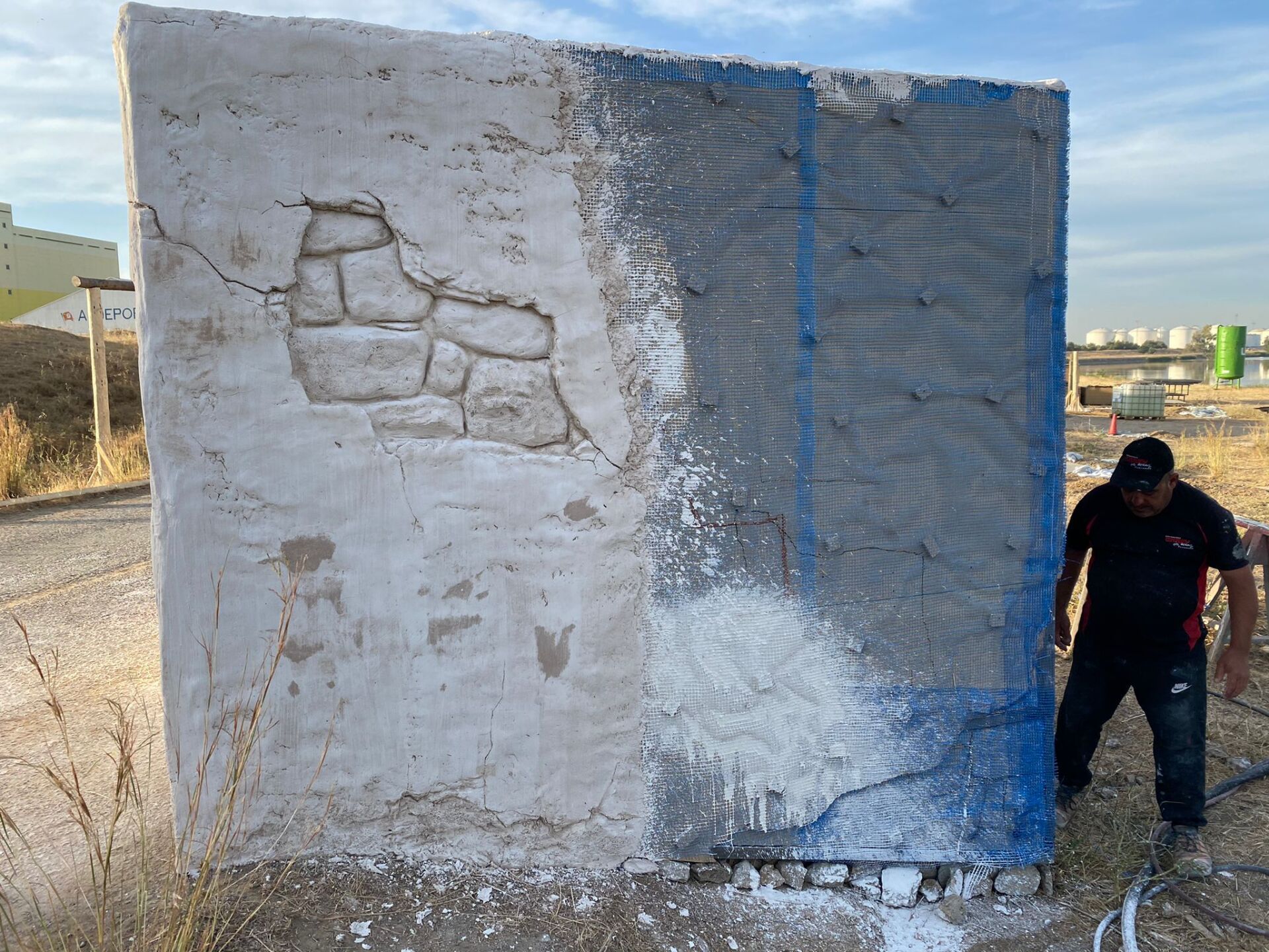 Un hombre está parado frente a una pared blanca y azul.