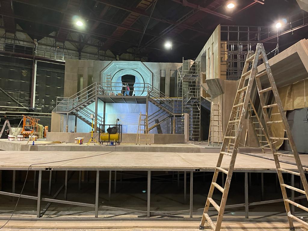 Se está construyendo un escenario en un gran edificio con una escalera en primer plano.