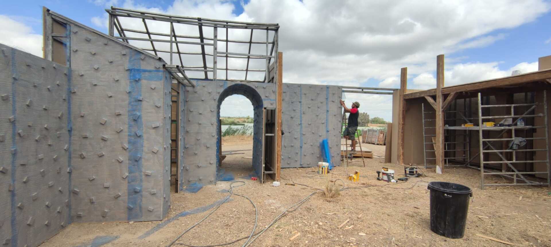 Un hombre está de pie sobre un andamio frente a un edificio en construcción.