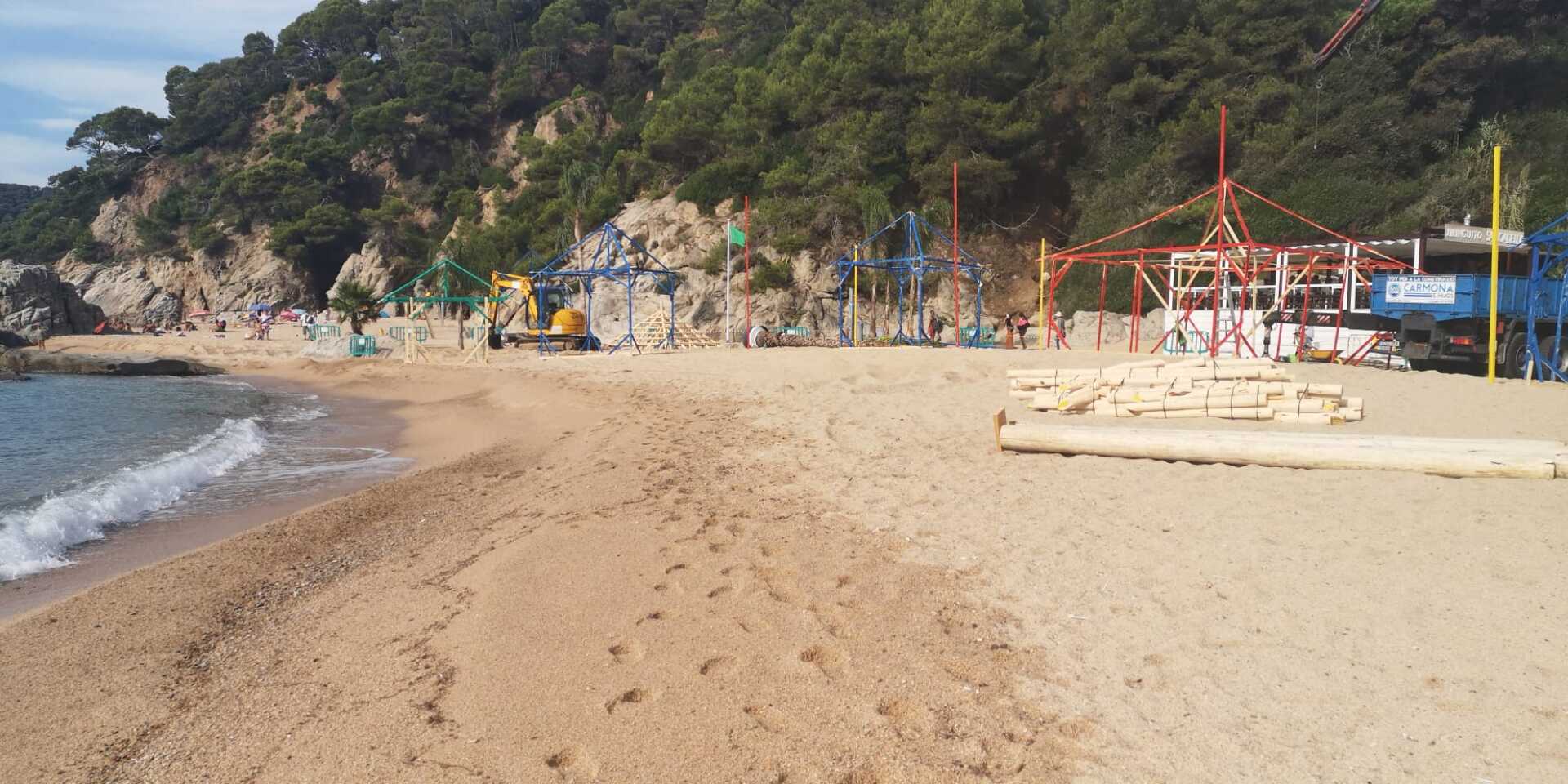 Una playa con una montaña rusa al fondo.