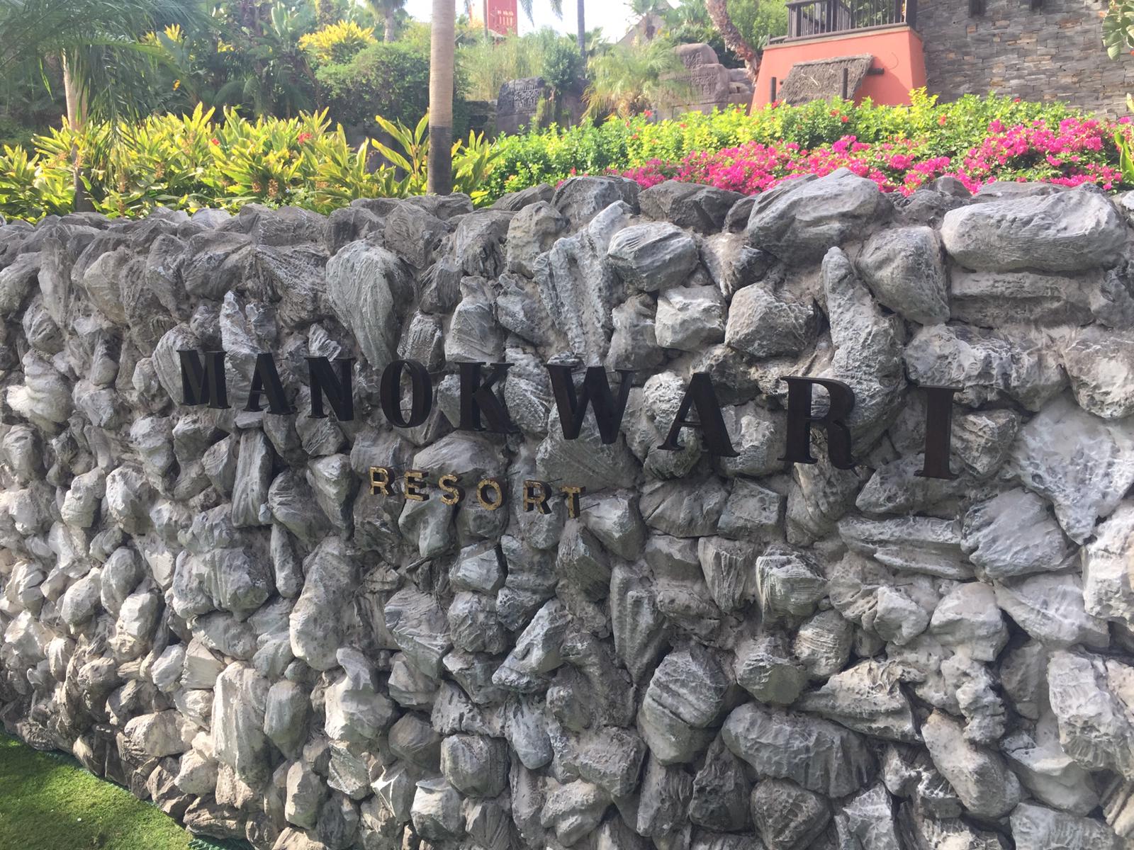 Un muro de piedra con las palabras Manor Ward Resort escritas en él.