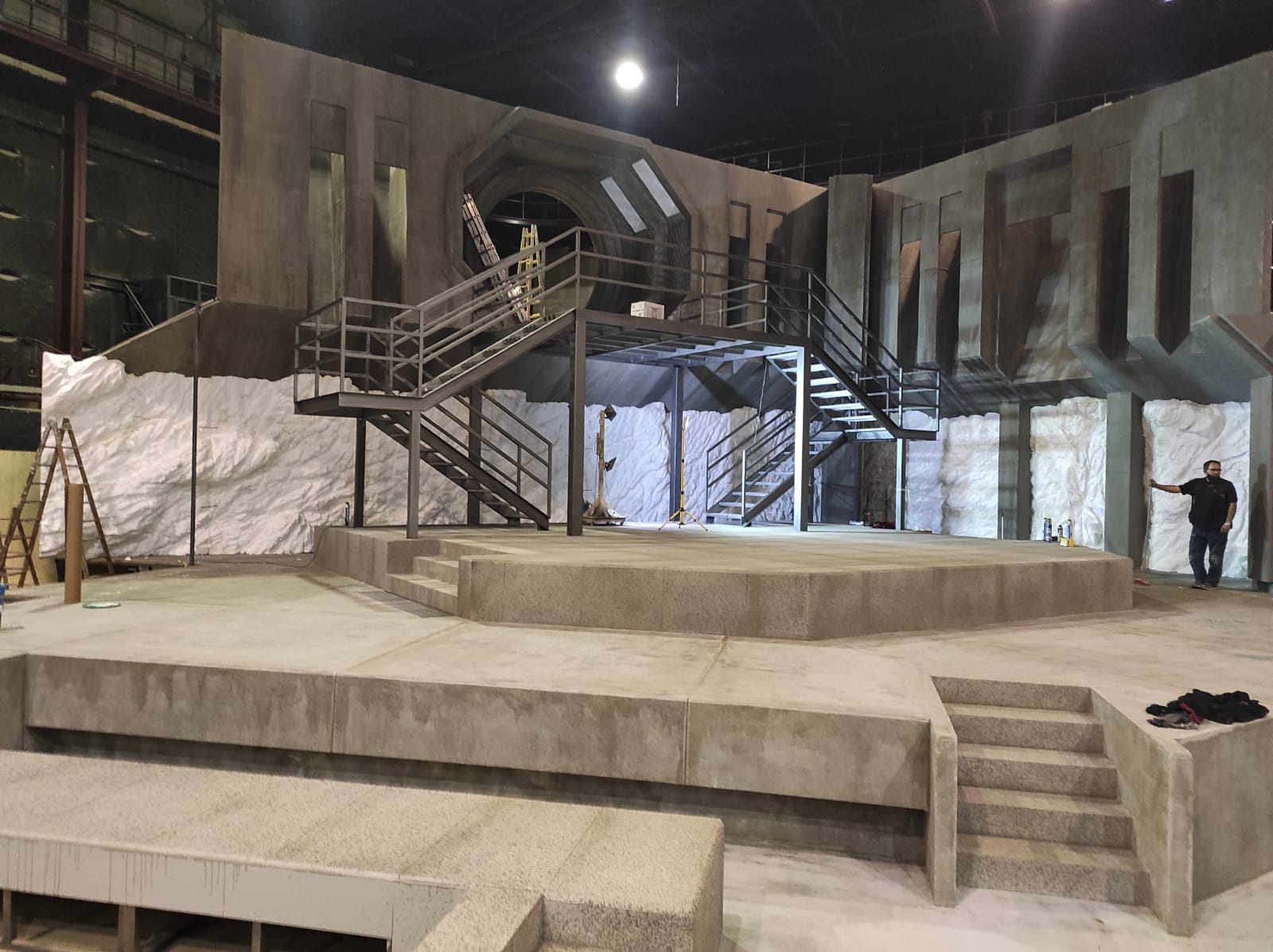 Un hombre está de pie en un escenario en un edificio con escaleras.