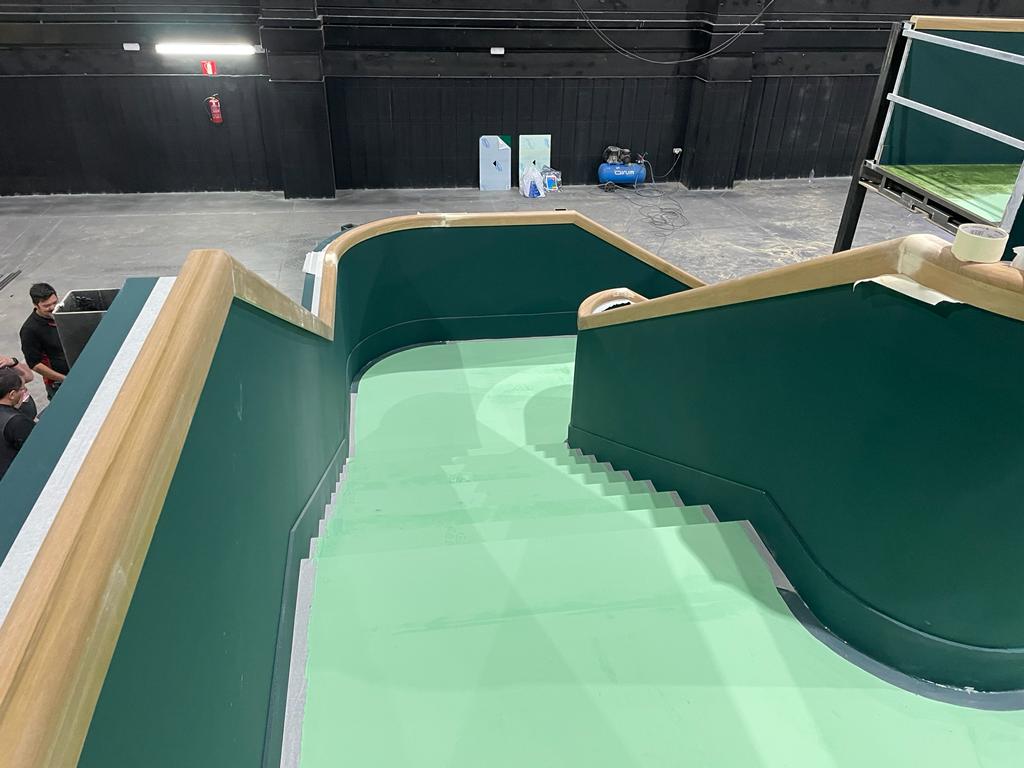 Una escalera verde con barandilla de madera en un edificio.