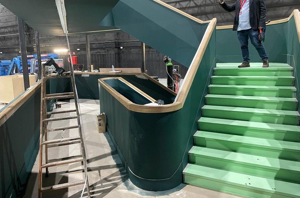 Un hombre está parado en lo alto de una escalera verde.