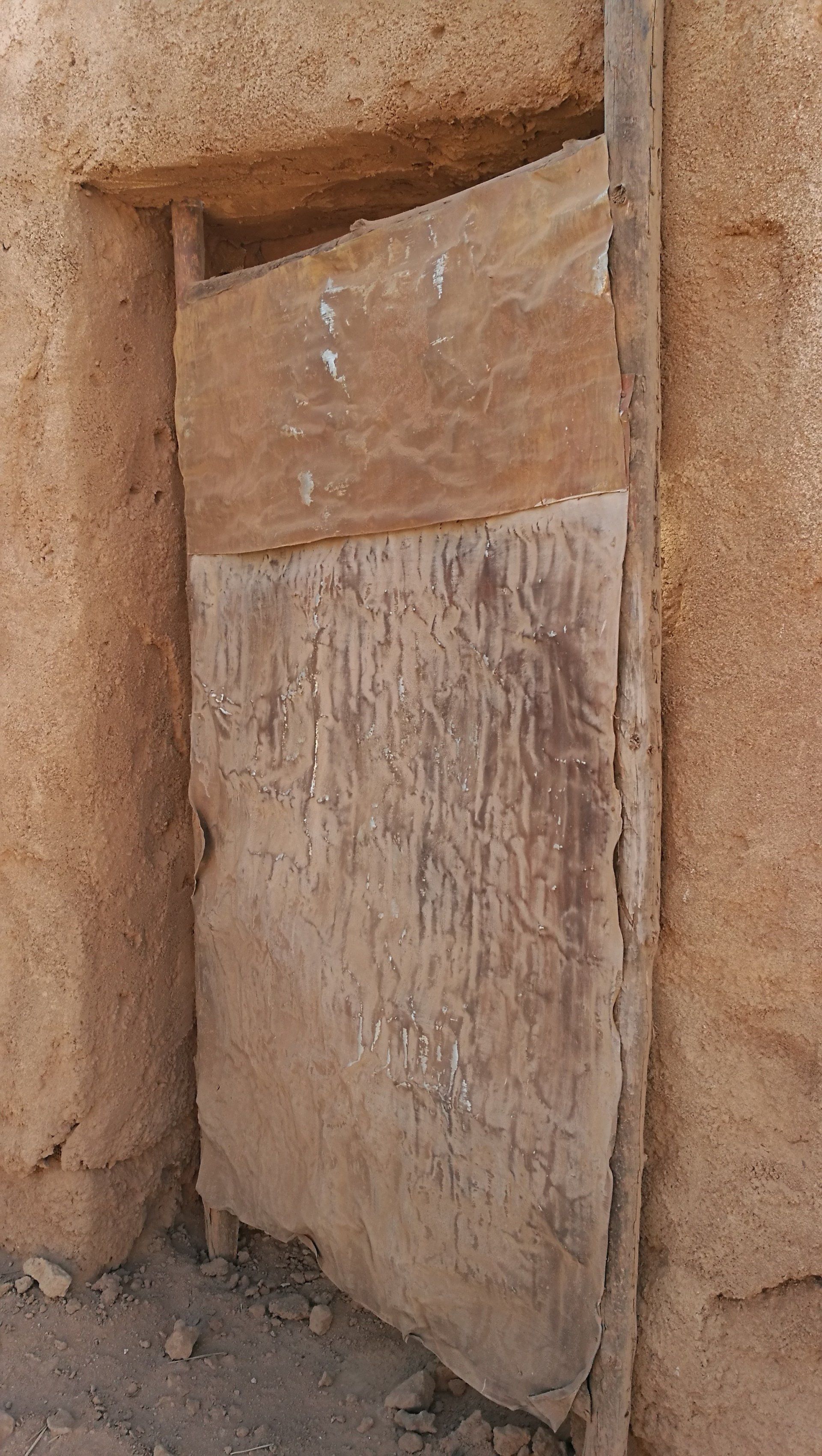 Una puerta de madera está sentada en el costado de un edificio.