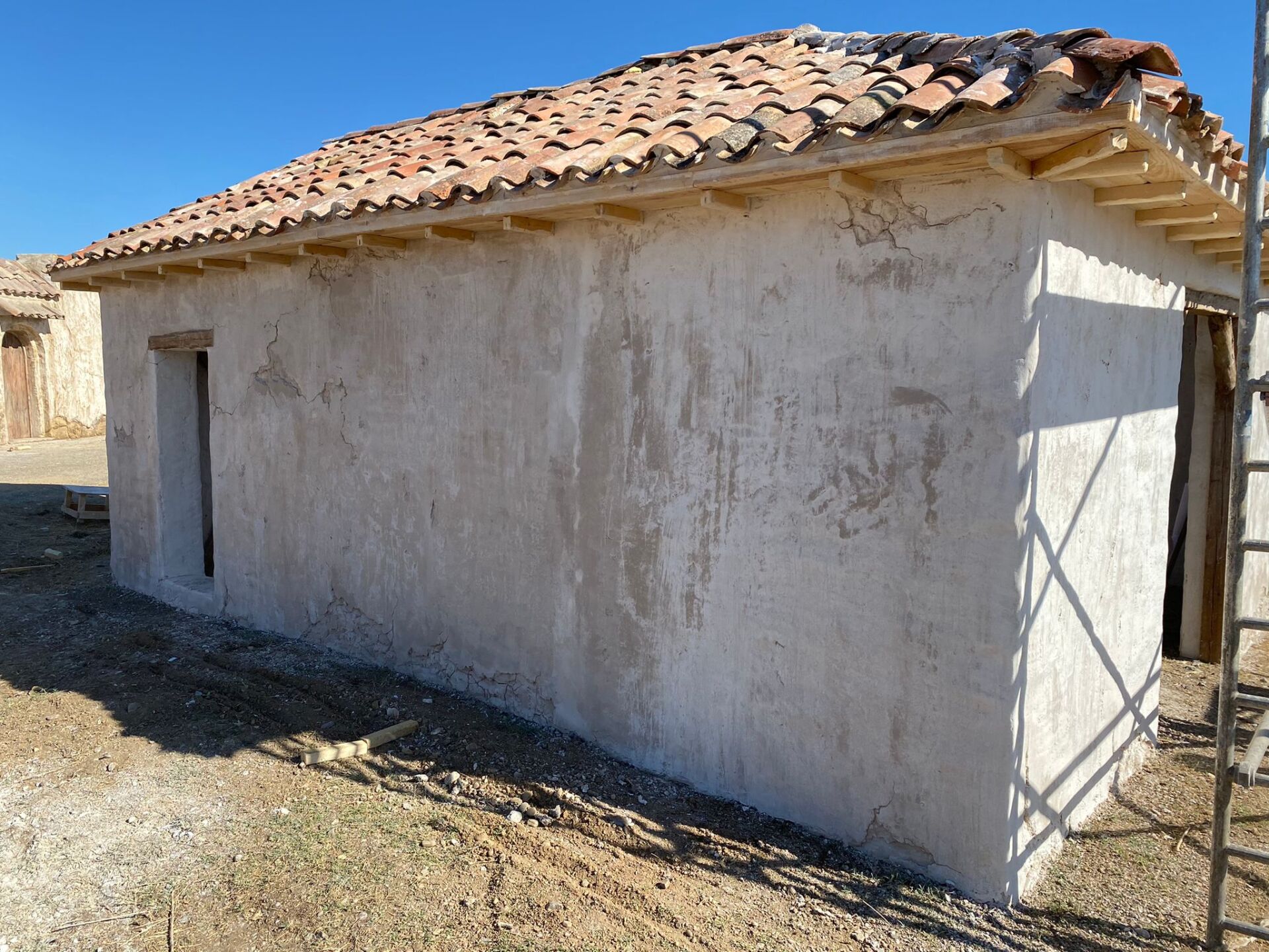 Un edificio blanco con techo de tejas y una escalera delante.