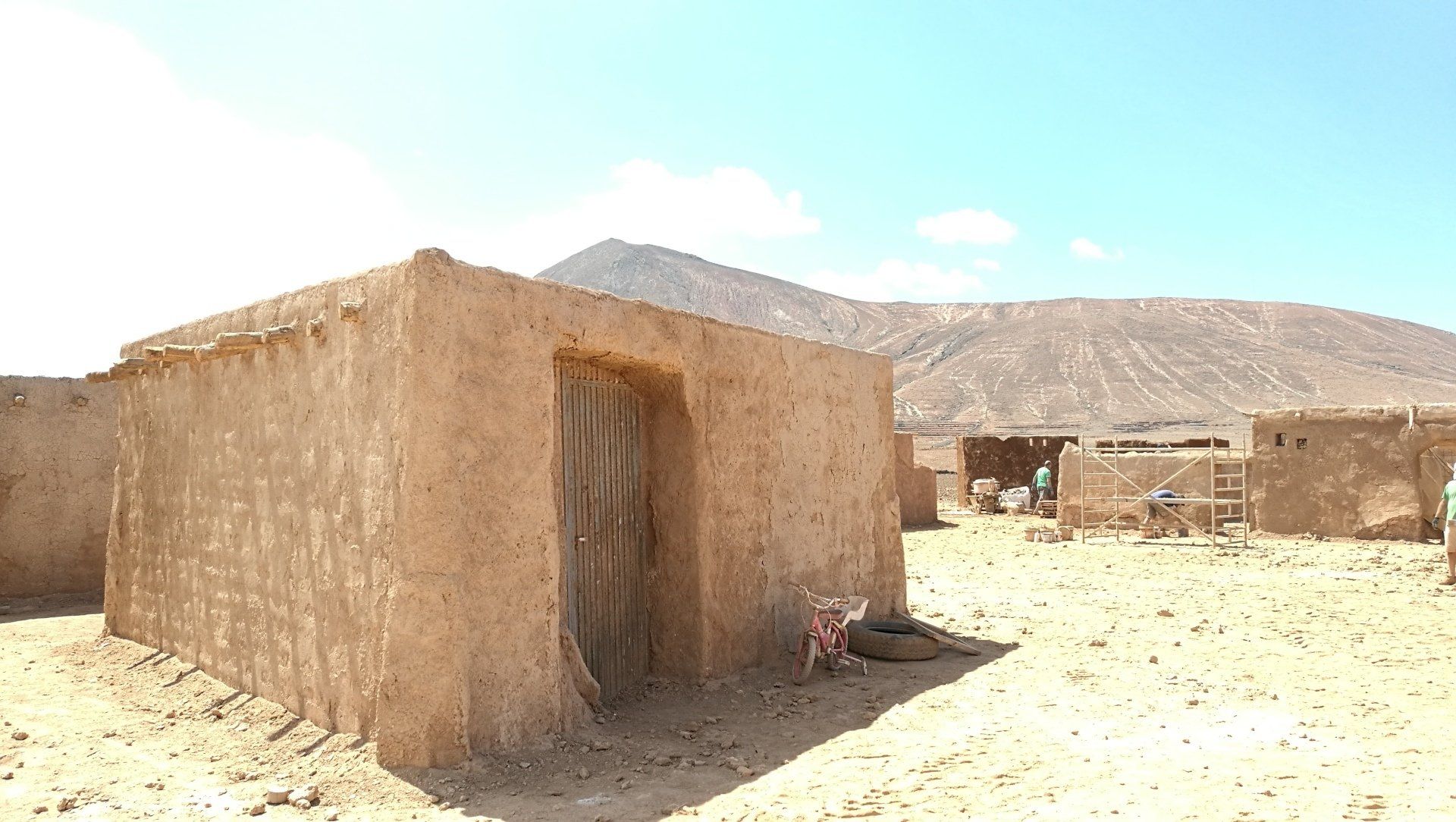 Un grupo de edificios en el desierto con montañas al fondo.