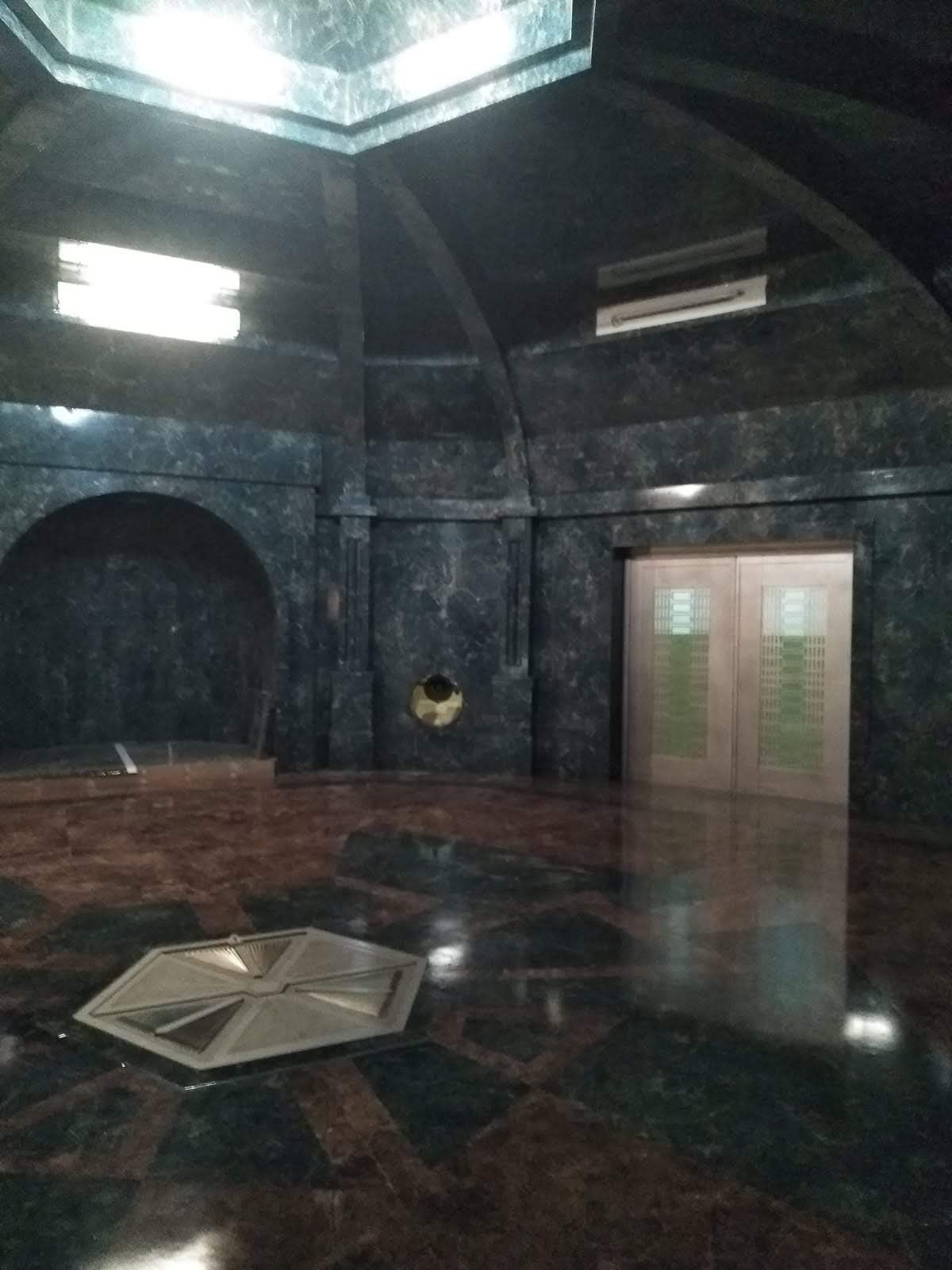 Una habitación oscura con suelo de mármol y una puerta.