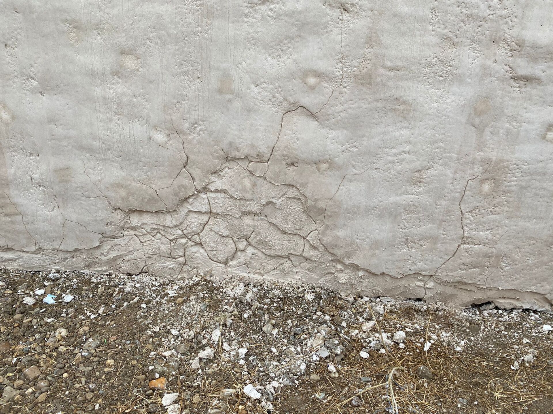 Un primer plano de un muro de hormigón agrietado junto a un camino de grava.