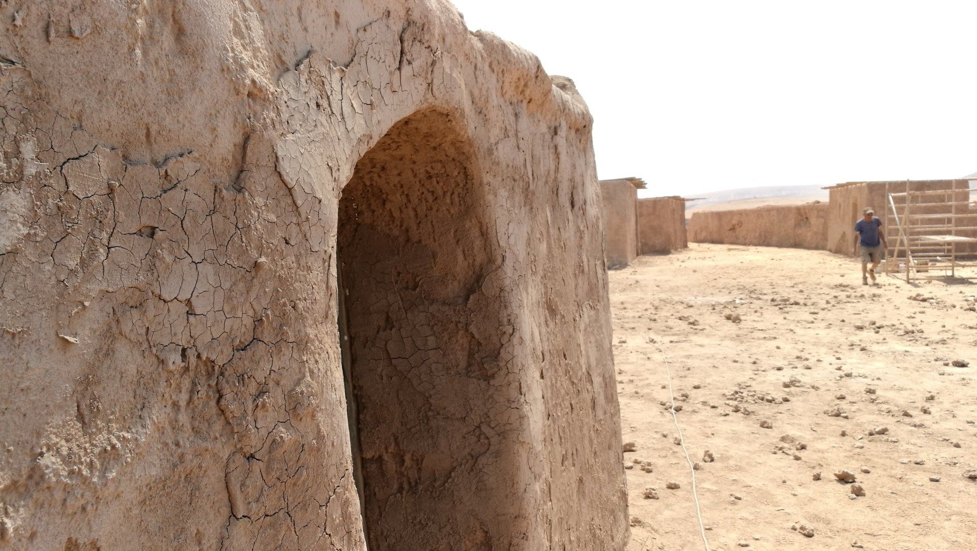 Un hombre con una chaqueta azul camina por el desierto.