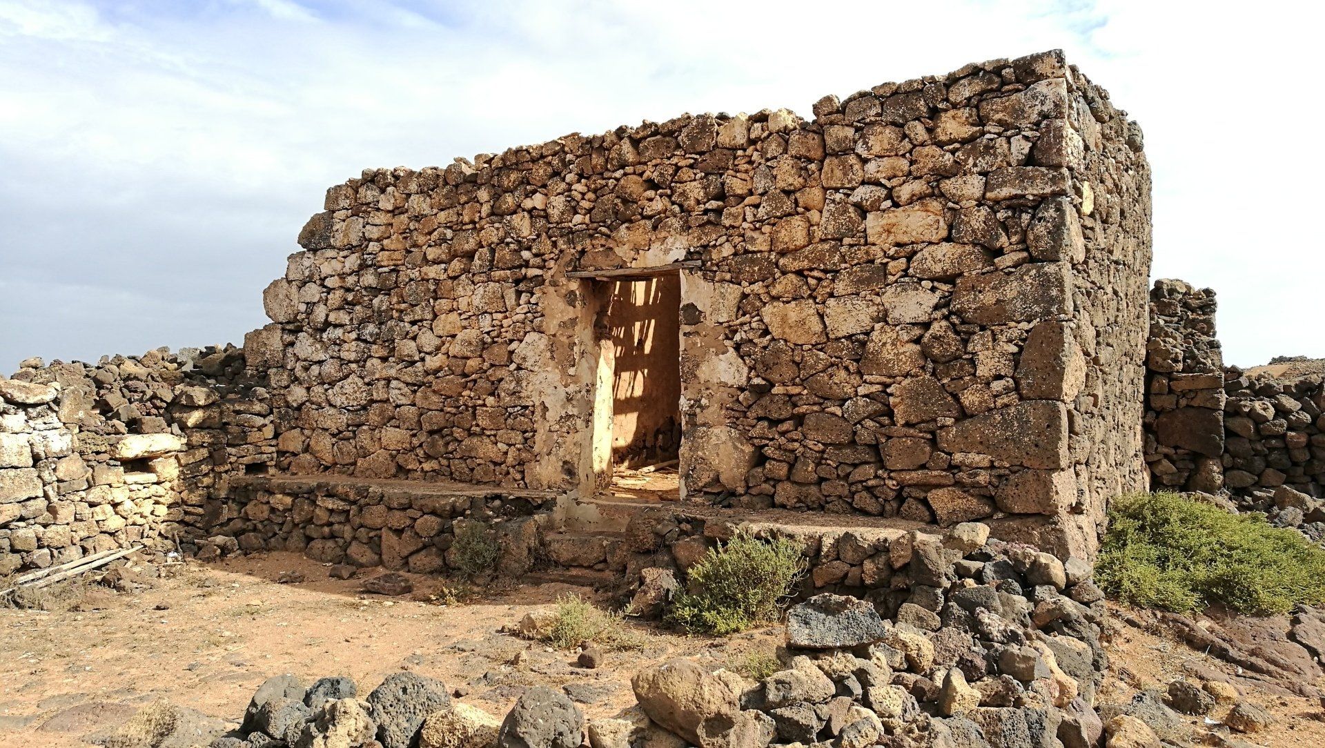 Un antiguo edificio de piedra con una puerta en medio del desierto.