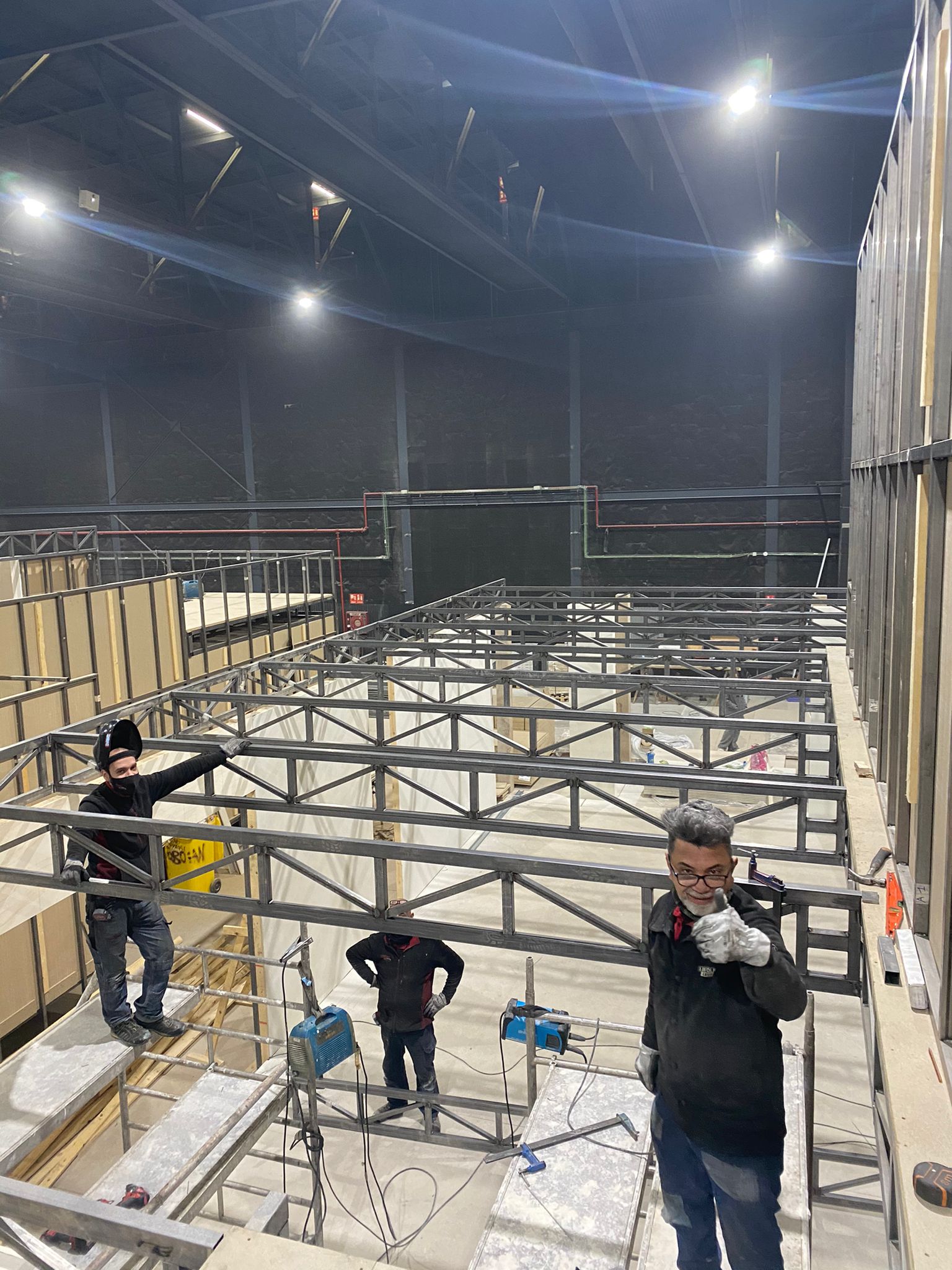 Dos hombres están trabajando en una estructura metálica en un edificio grande.