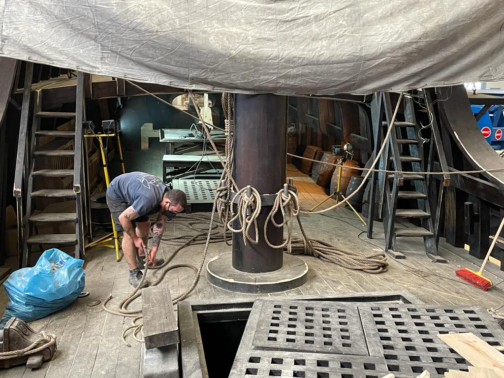 Un hombre está trabajando en un barco en un almacén.