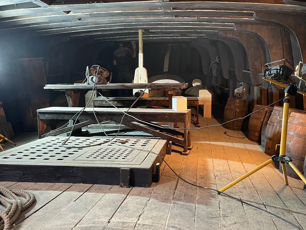 El interior de un barco con suelo de madera y barriles.