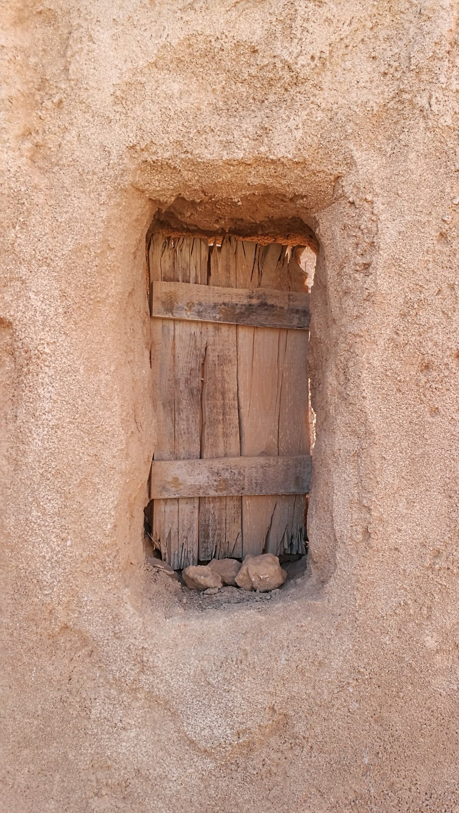Una pequeña ventana de madera en una pared de piedra.