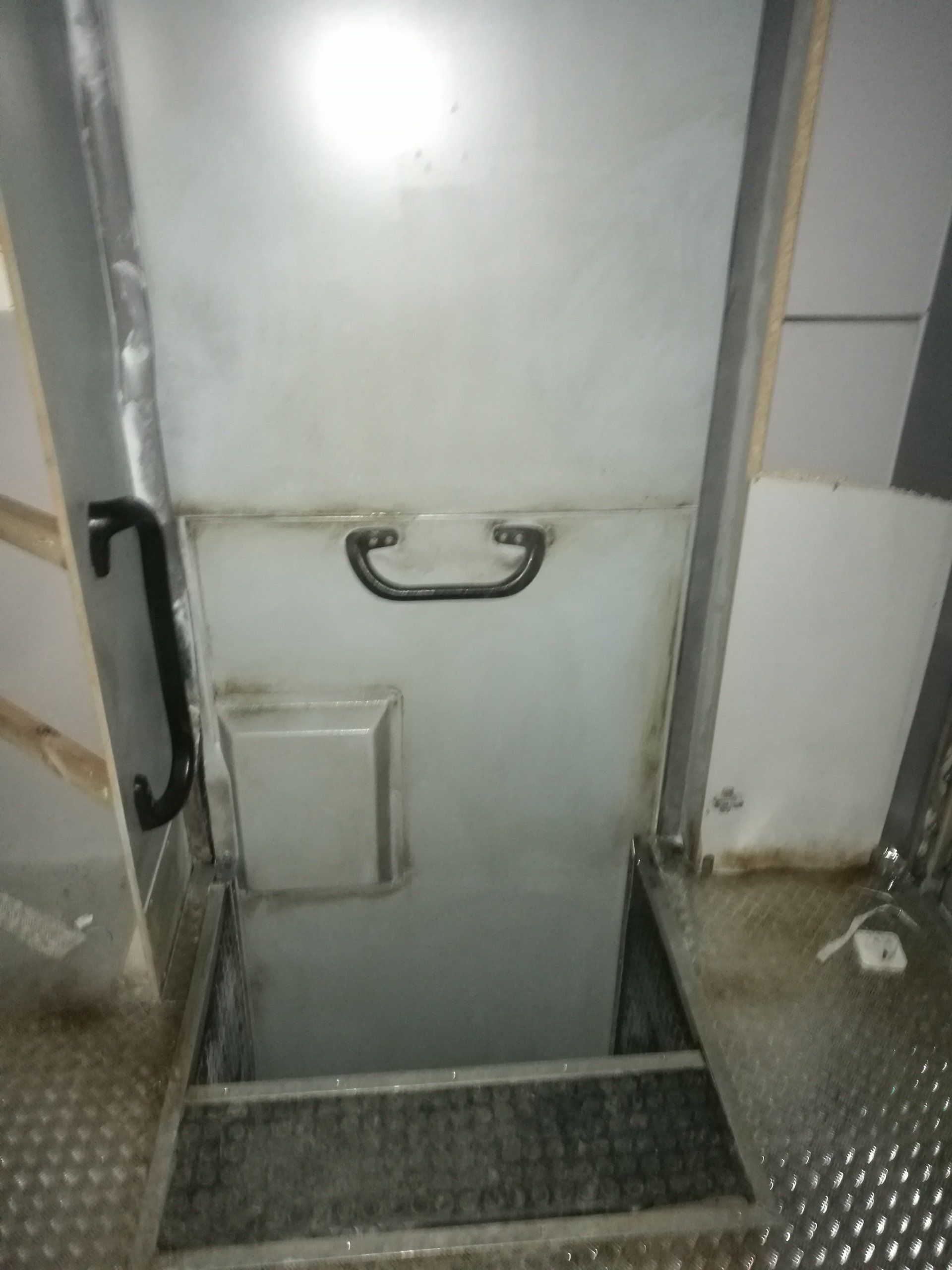 Una puerta blanca con manija negra está abierta en una habitación.