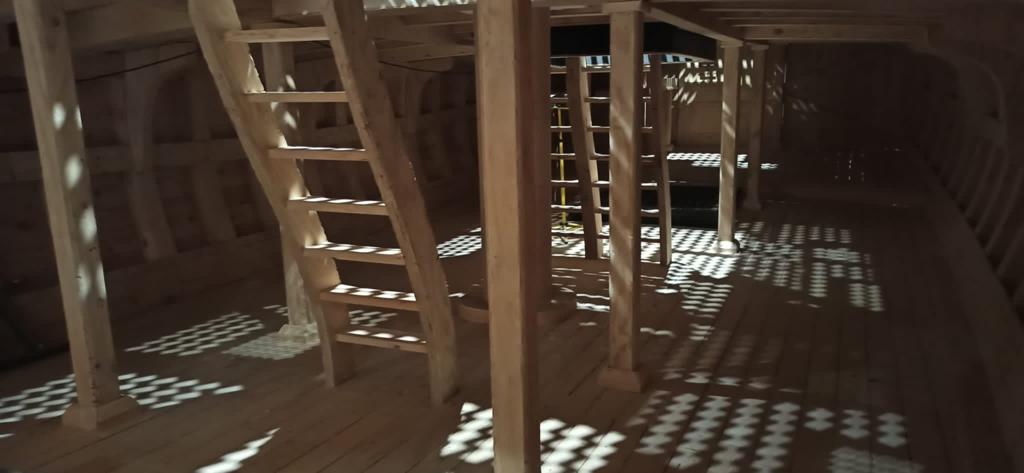 Una estructura de madera con escaleras y un reflejo del sol en el suelo.