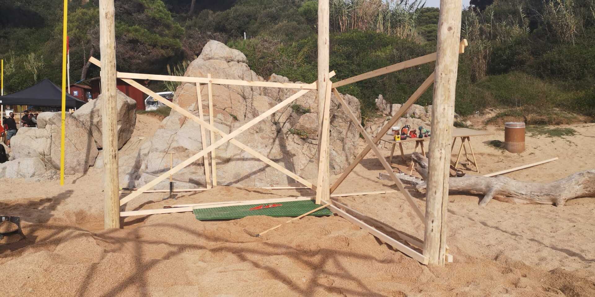 Se está construyendo una valla de madera en una playa de arena.