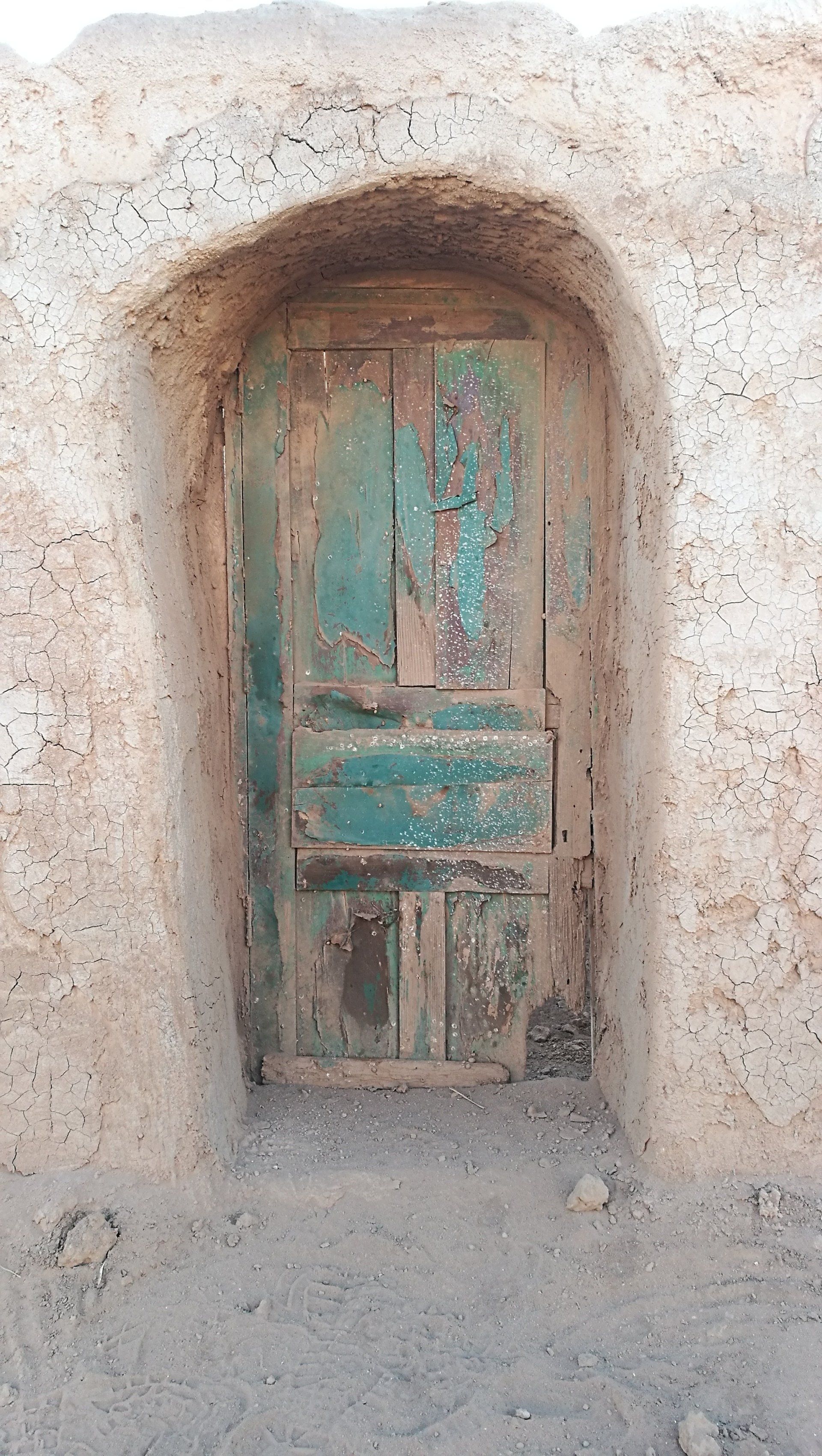 Una vieja puerta de madera se encuentra en el medio de una pared de piedra.