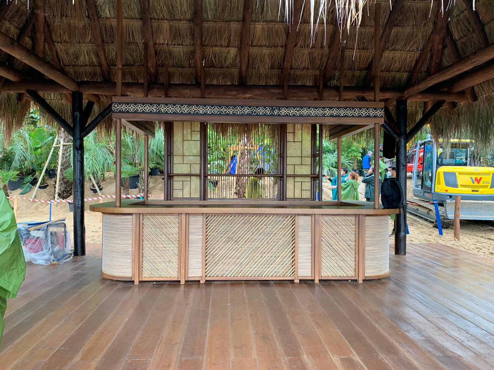Una barra de madera bajo un techo de paja está colocada sobre un suelo de madera.
