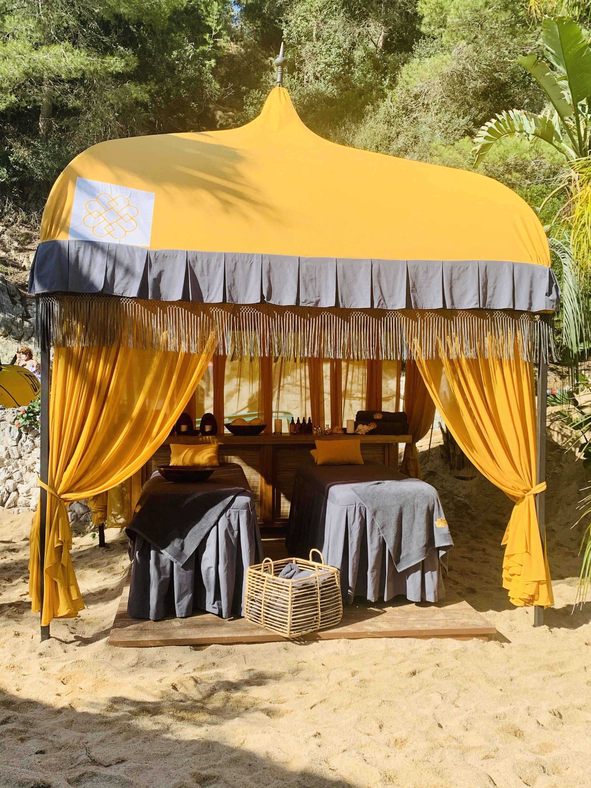 Una carpa amarilla y gris con mesas debajo.