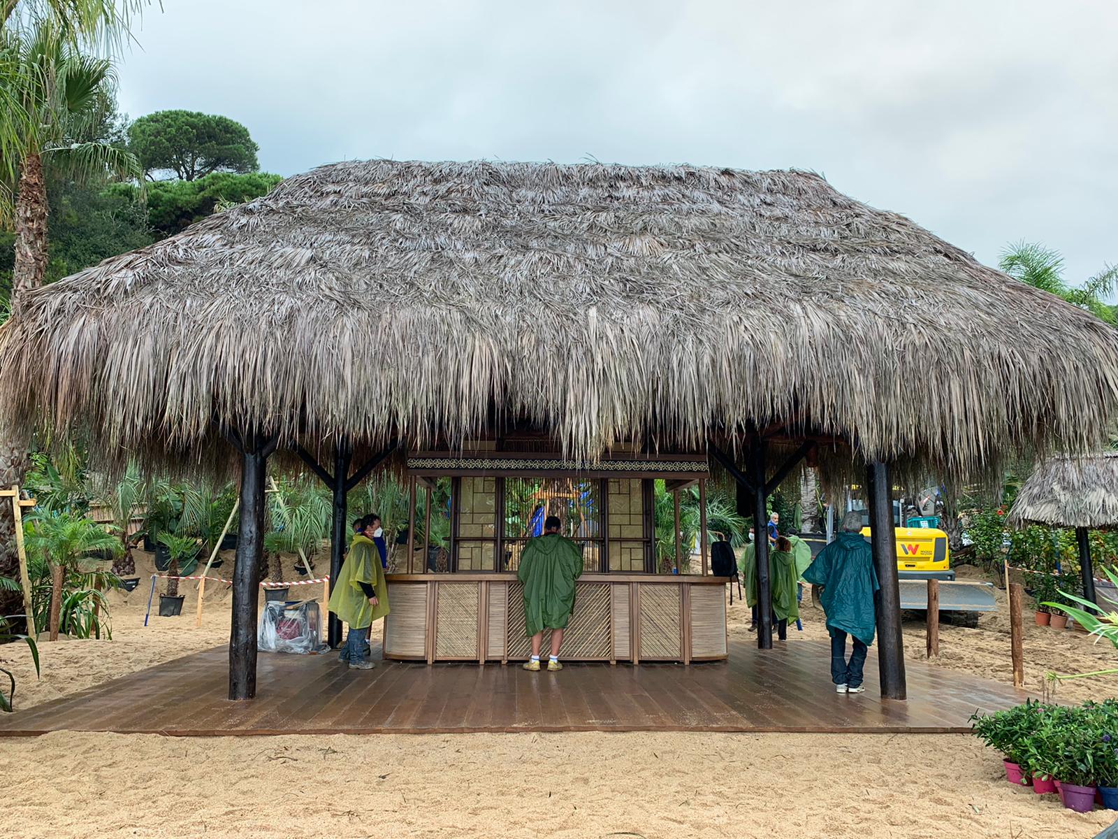 Una choza con techo de paja, un bar y gente de pie alrededor.