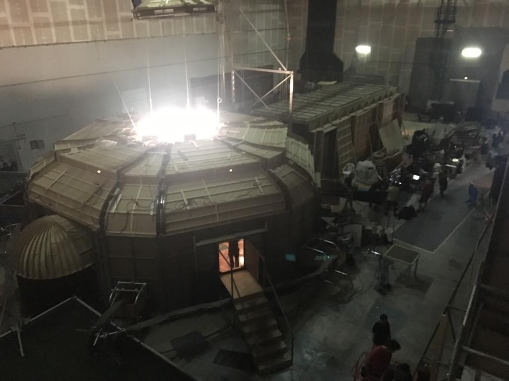 Un grupo de personas está de pie alrededor de un gran edificio por la noche.