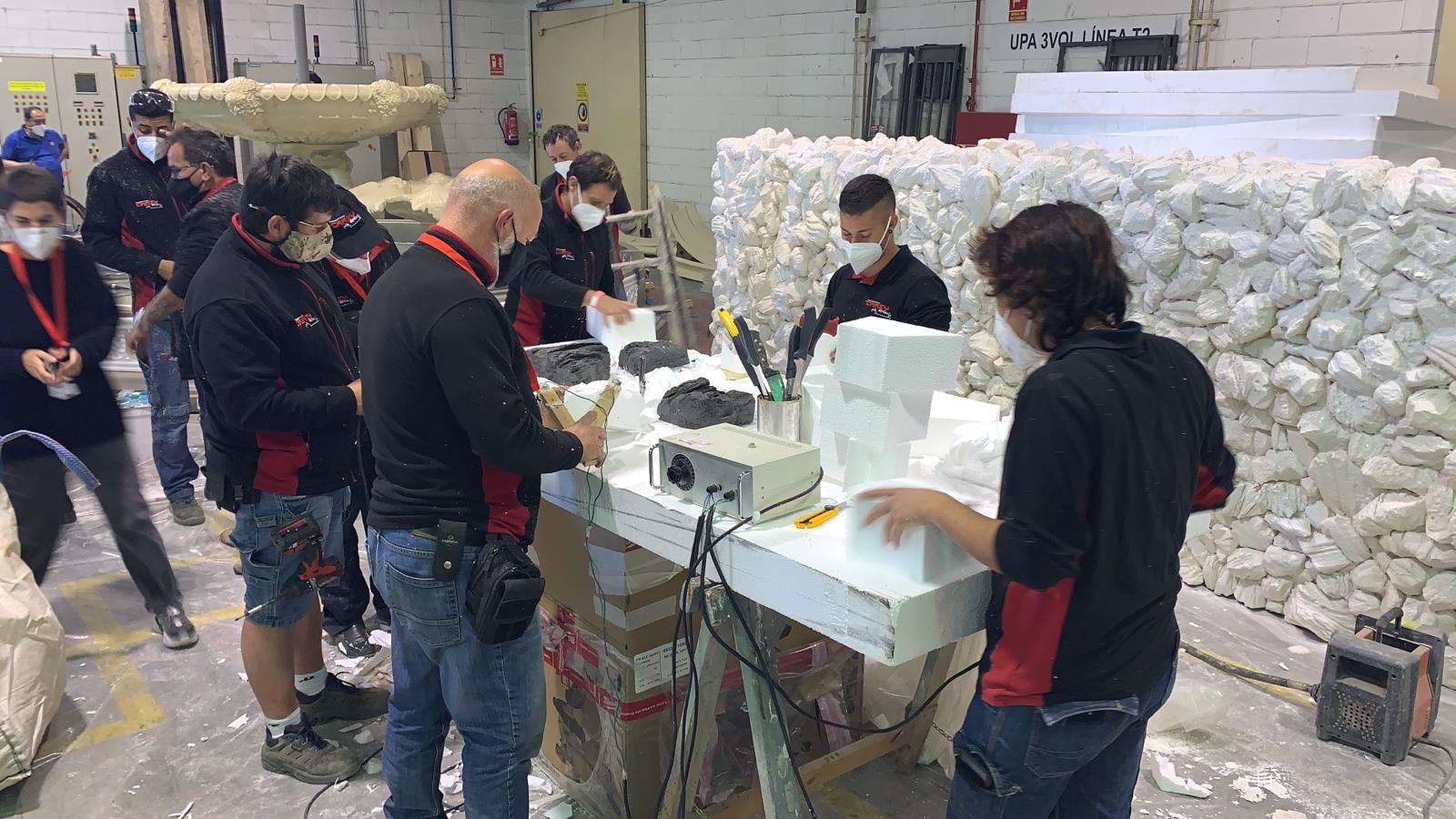 Un grupo de personas están de pie alrededor de una mesa en una fábrica.