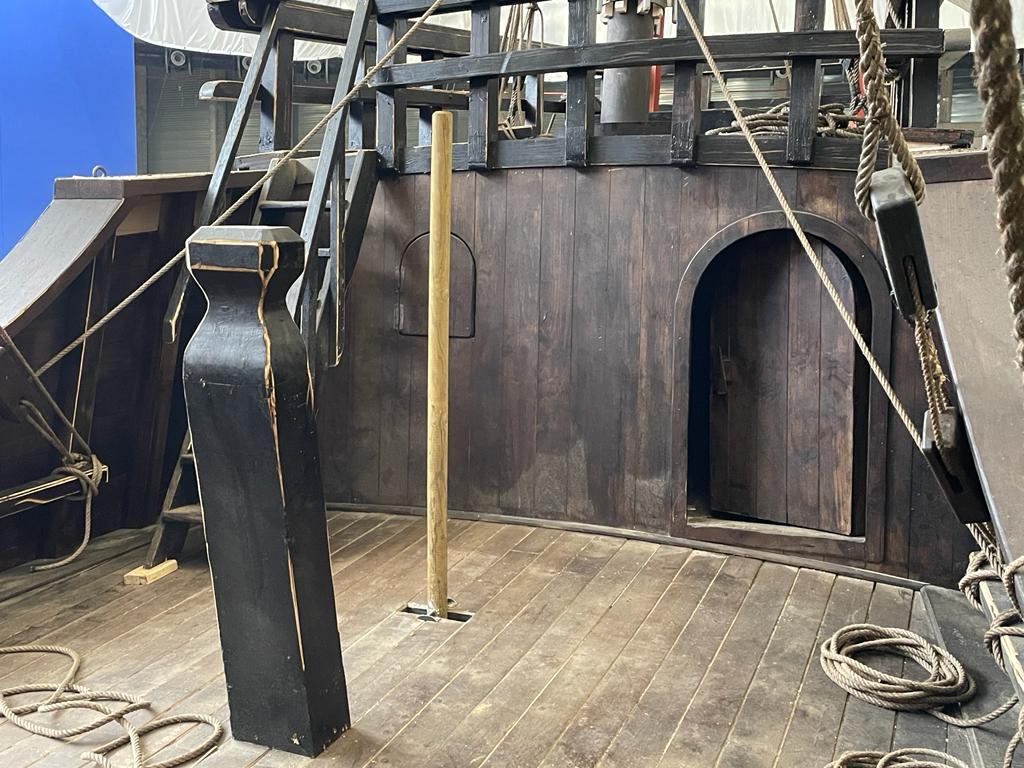 El interior de un barco pirata de madera con cuerdas y escaleras.