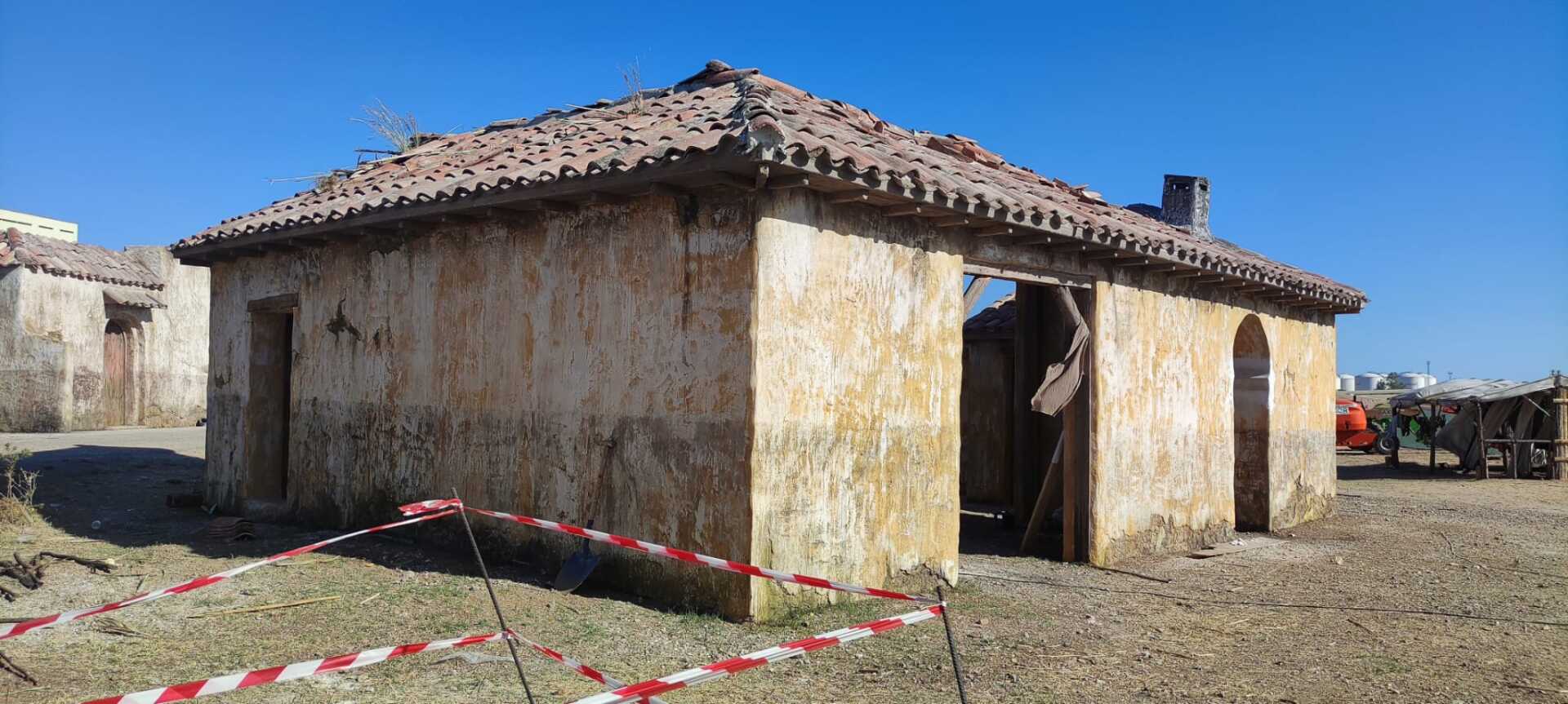 Un edificio antiguo con techo de tejas está rodeado por una cinta roja y blanca.