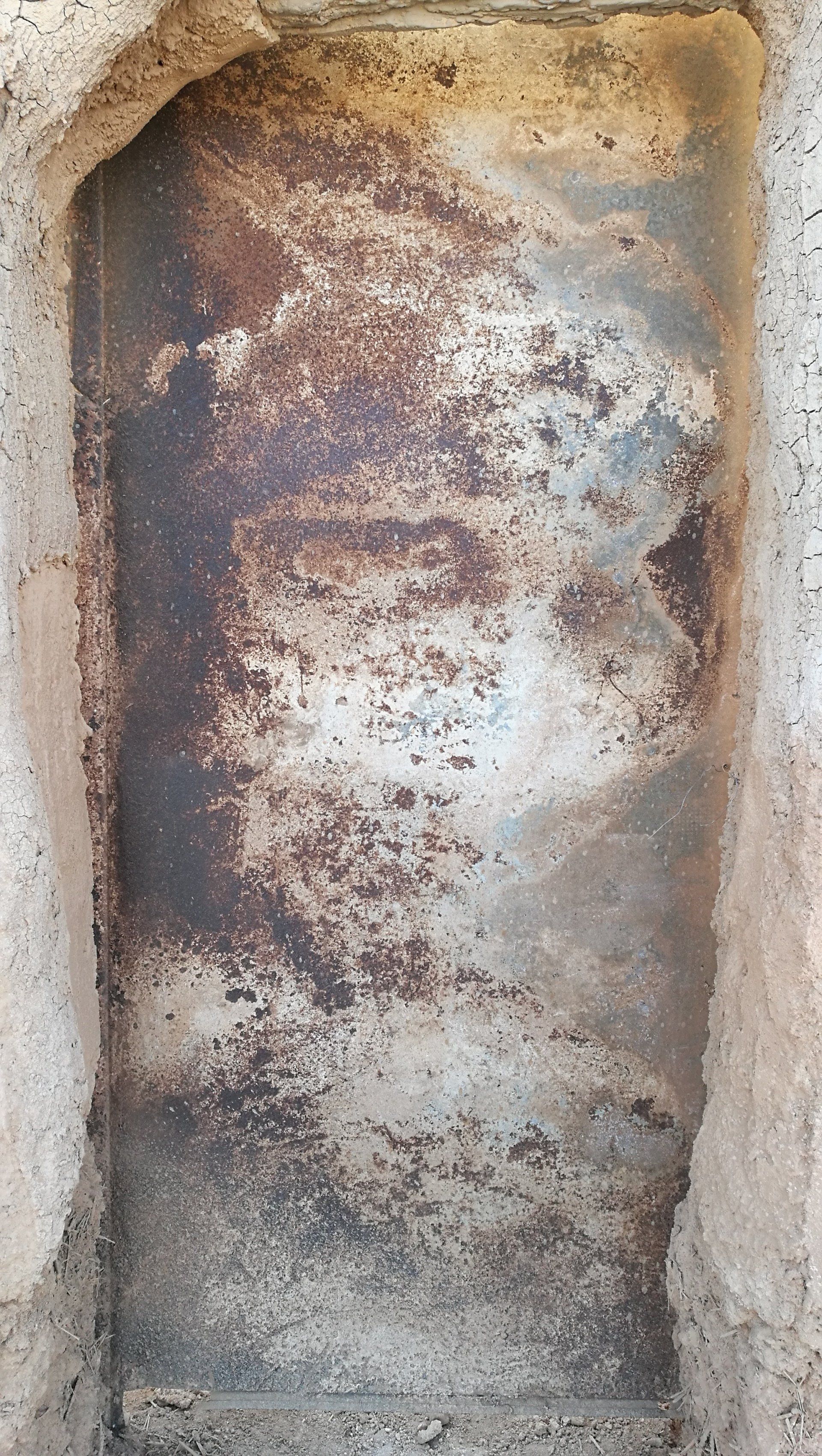 Un trozo de metal oxidado está en un agujero en una pared.